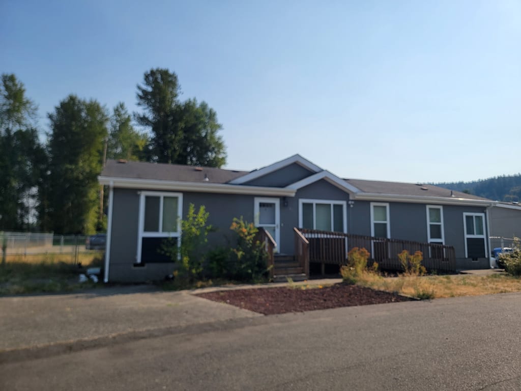 Gray manufactured home with fresh white seamless gutters running the full roofline.
