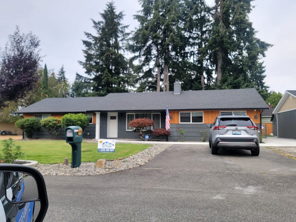 Seamless gutter work on a Pacific Northwest home with a Seamless Gutters 4 Less yard sign.