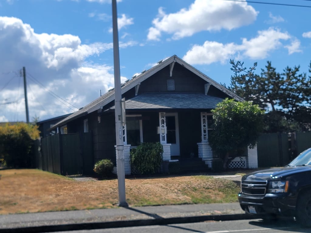 Dark green craftsman bungalow with white porch columns, gutter work by Seamless Gutters 4 Less.